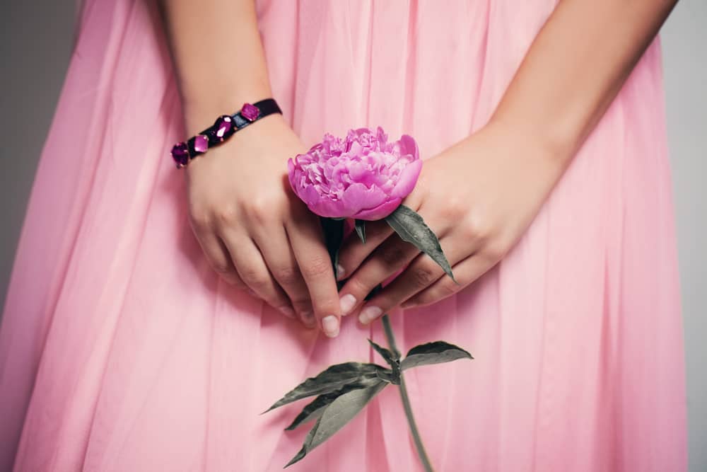一輪の花を手にする女性の画像。服装はピンク。